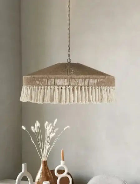 Pendant light with tassels hanging above a dining table with decorative items Besontique Home