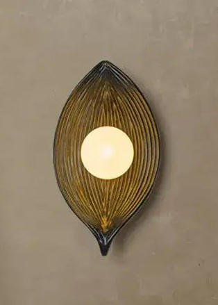 Decorative wall sconce with a leaf-shaped design on a beige wall.