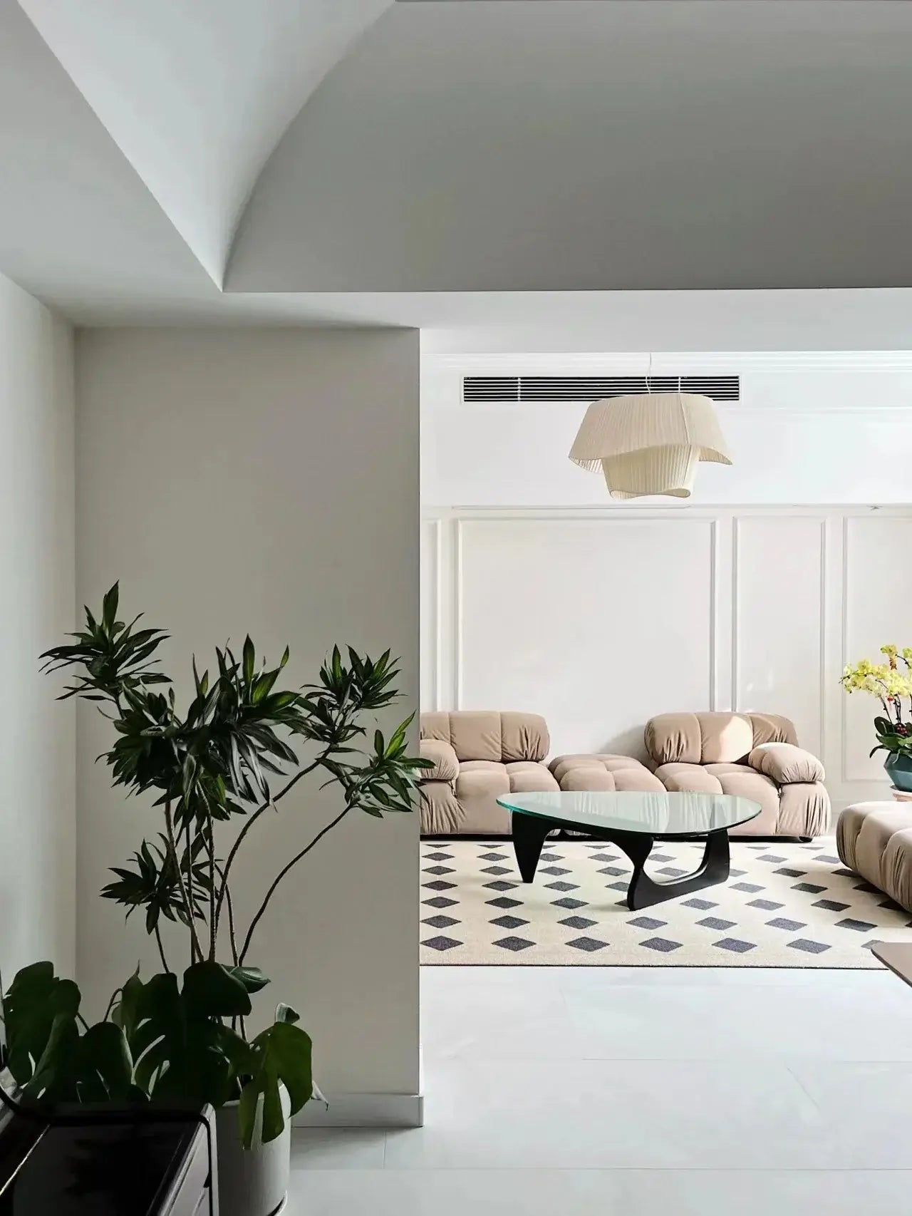 Modern living room with beige sofa, coffee table, and decorative plants.